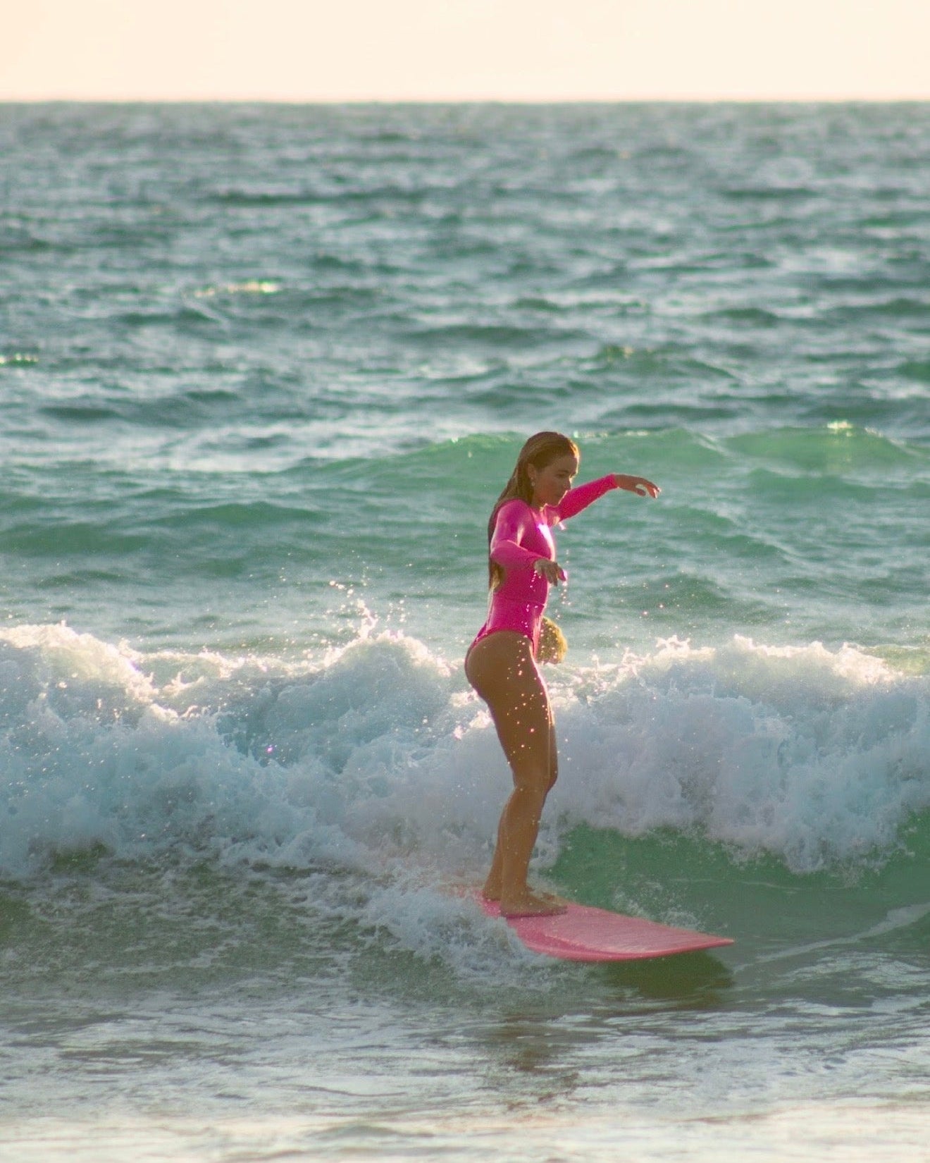 Person surfing on a pink surfboard in the ocean